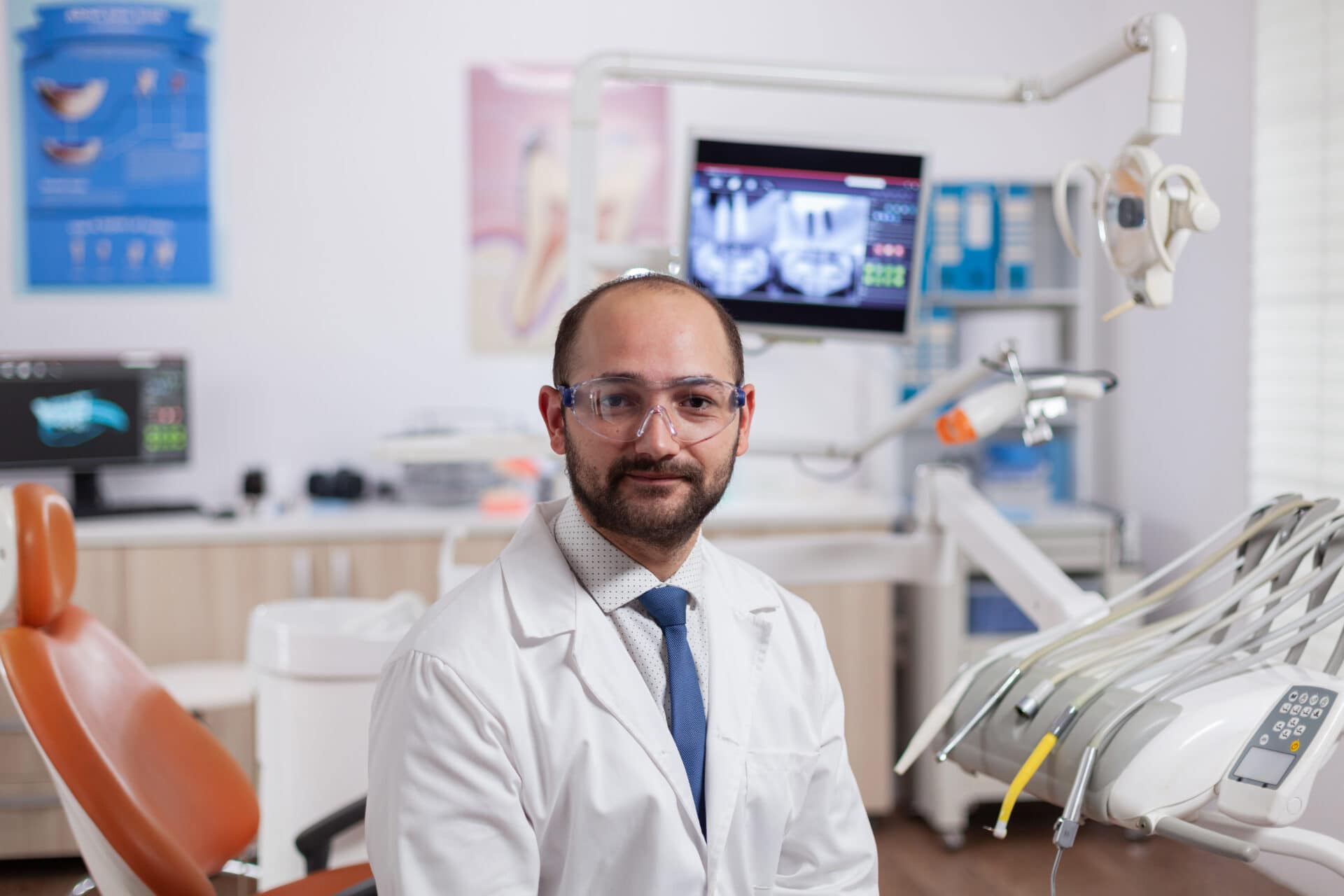 confident dentist in stomatology cabinet smiling at camera