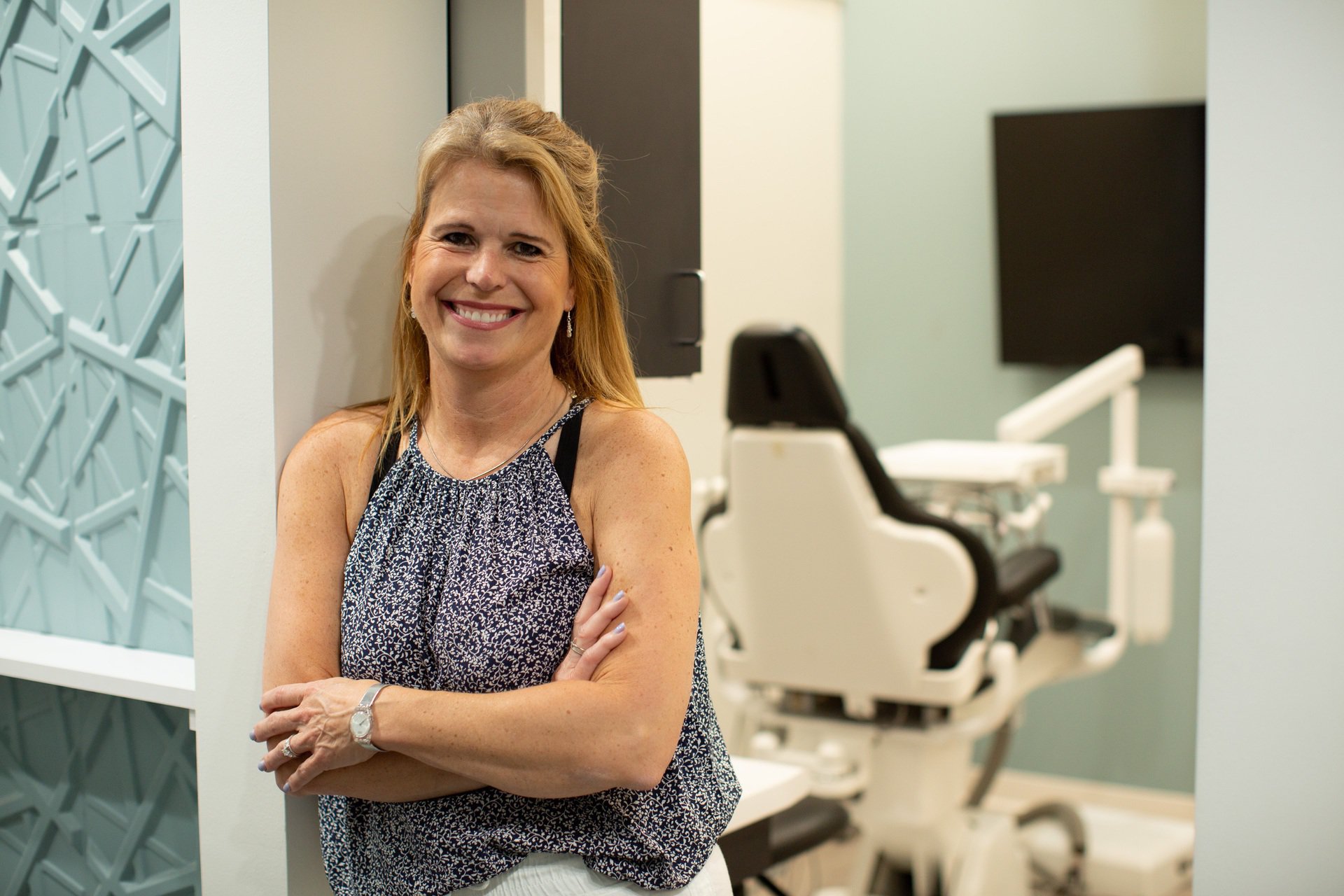 Laura Nelson smiling, standing in front of a dental chair