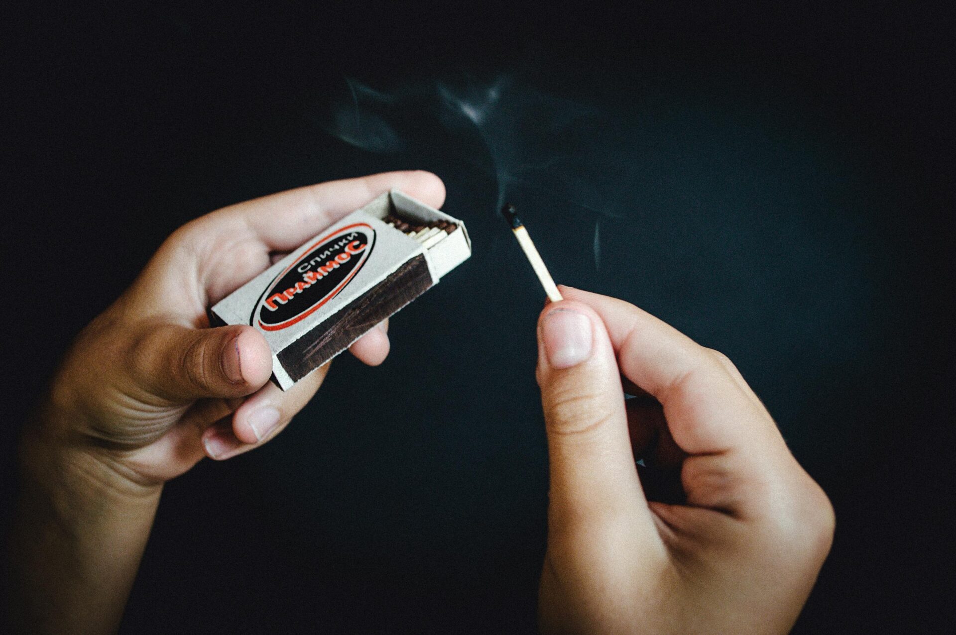 hands holding match box and smoking spent match. from pexels